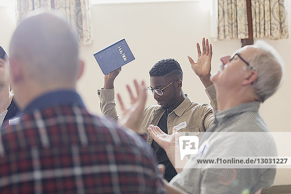 Männer mit Bibel beten mit erhobenen Armen in einer Gebetsgruppe