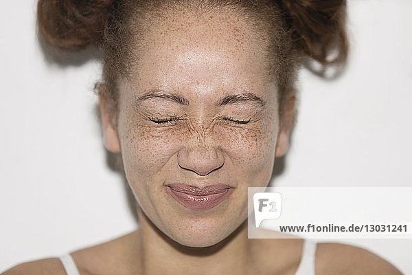 Portrait playful young woman with freckles squeezing eyes shut