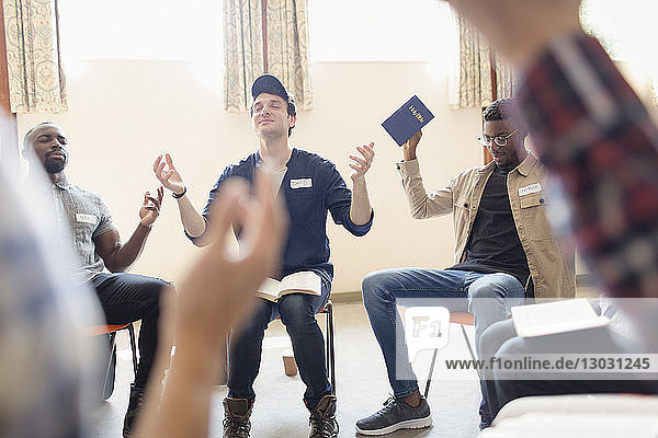 Männer mit Bibel beten mit erhobenen Armen in einer Gebetsgruppe