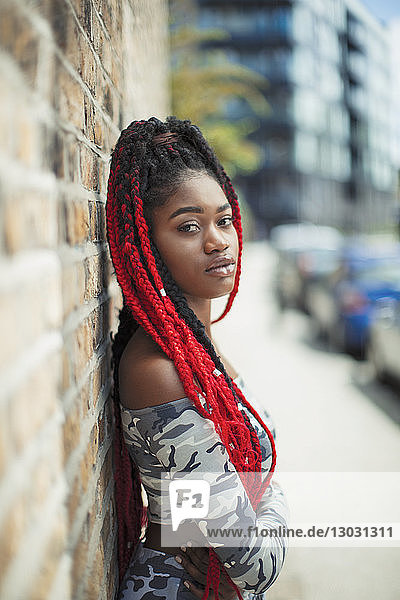 Portrait confident young woman with long red braids on urban sidewalk