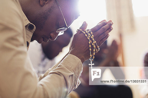 Mann betet mit Rosenkranz in Gebetsgruppe