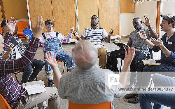 Männer beten mit erhobenen Armen in einer Gebetsgruppe