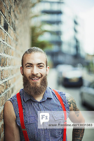 Porträt eines selbstbewussten  lächelnden männlichen Hipsters auf einem Bürgersteig