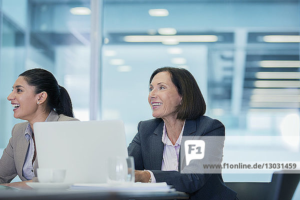 Smiling businesswomen listening in conference room meeting