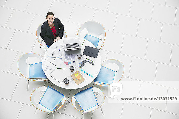High angle portrait confident businesswoman sitting at round table