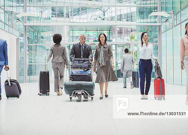 Business people walking with luggage in airport