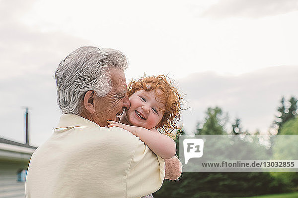 Female toddler with curly red hair in grandfather's arms  portrait