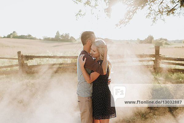 Romantischer Mann und Freundin umarmen sich bei Sonnenuntergang auf staubiger Piste