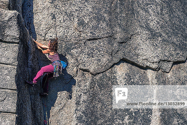 Junge weibliche Felskletterin beim Klettern an einer Felswand  in voller Länge  Seitenansicht  Smoke Bluffs  Squamish  British Columbia  Kanada