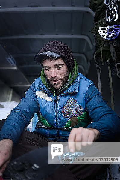 Junger männlicher Bergsteiger bereitet Kletterausrüstung im Wohnmobil vor