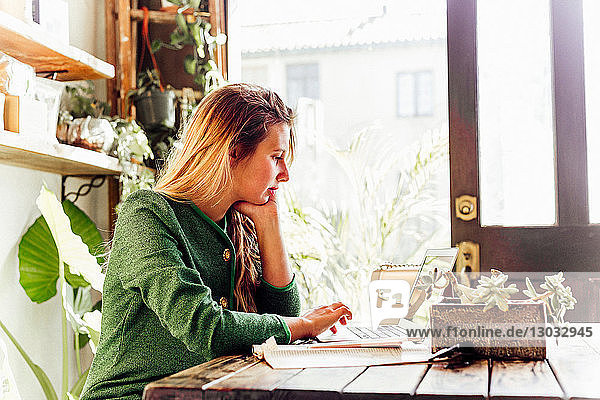 Junge Frau benutzt Laptop im Café