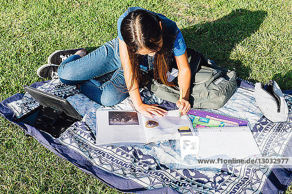 Girl doing homework on grass