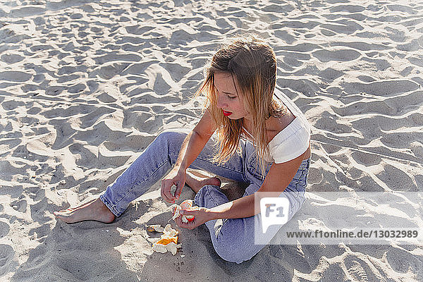 Junge Frau schält Früchte am Strand