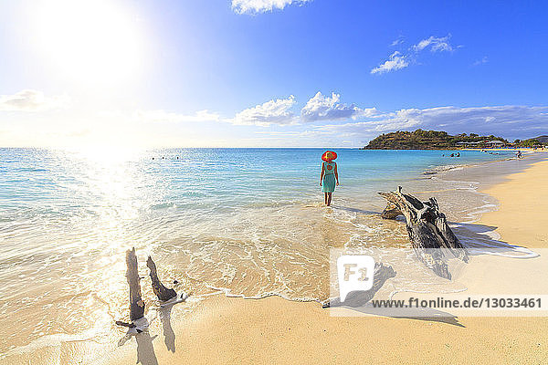 Rückansicht einer Frau mit Hut  die am Ffryes Beach spazieren geht  Antigua  Antigua und Barbuda  Leeward Islands  Westindien  Karibik