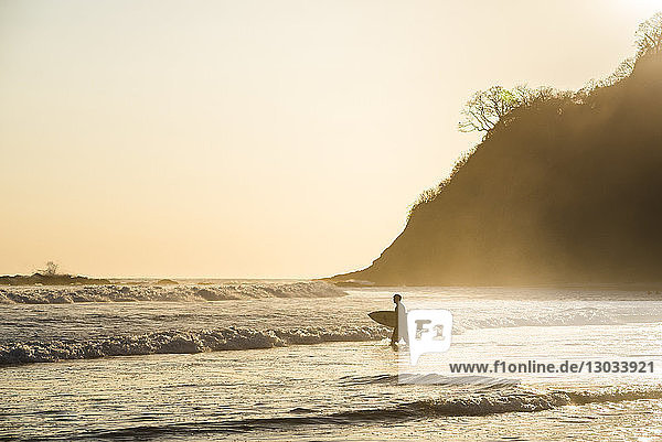Surfers surfing on a beach at sunset  Nosara  Guanacaste Province  Pacific Coast  Costa Rica