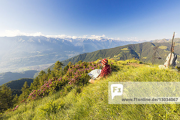 Wanderer mit Fernglas und Karte blickt vom Pizzo Berro  Bitto-Tal  Lombardei  Italien  auf die Rätischen Alpen und den Monte Disgrazia