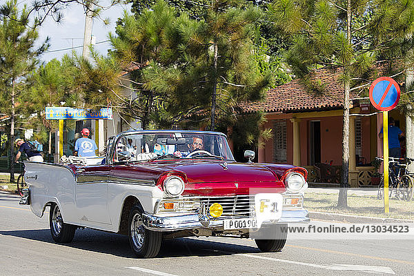Rotes und weißes Cabrio-Oldtimertaxi auf der Hauptstraße in Vinales  UNESCO-Weltkulturerbe  Kuba  Westindien  Karibik