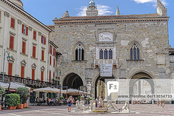 Old Town Palace (Palazzo della Ragione) on Piazza Vecchia with fountain and crowd in Citta Alta  Bergamo  Lombardy  Italy