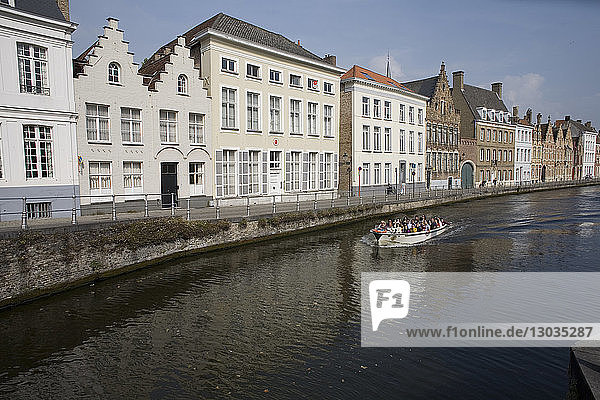 Spinolarei Canal with buildings on Sint-Annarei and approaching boat carrying tourists  Bruges  Belgium