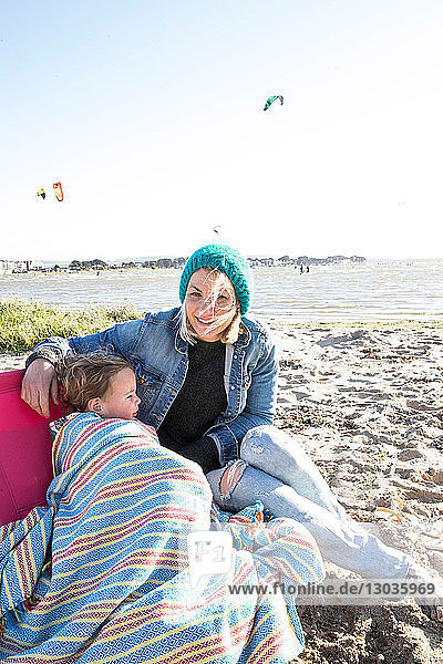 Mutter und Kleinkind Mädchen in Decke am Strand