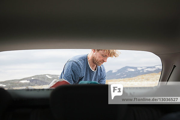Blick auf die Motorhaube eines reifen Mannes beim Auspacken des Autos  Oppland  Nord-Trondelag  Norwegen