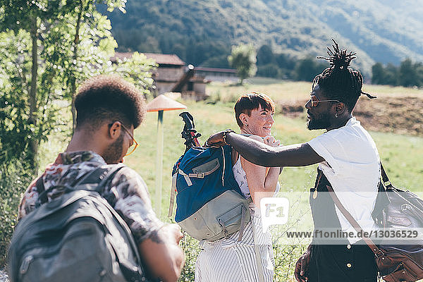 Three young adult hiking friends preparing rucksacks in field