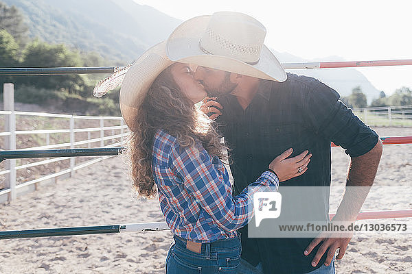 Junges Cowgirl und Freund küssen sich in ländlicher Reitarena