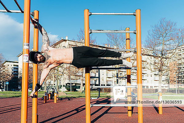 Mann benutzt horizontale Leiter im Fitnessstudio im Freien
