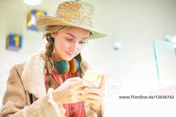 Junge Frau am Flughafen  mit Smartphone  Kopfhörer um den Hals