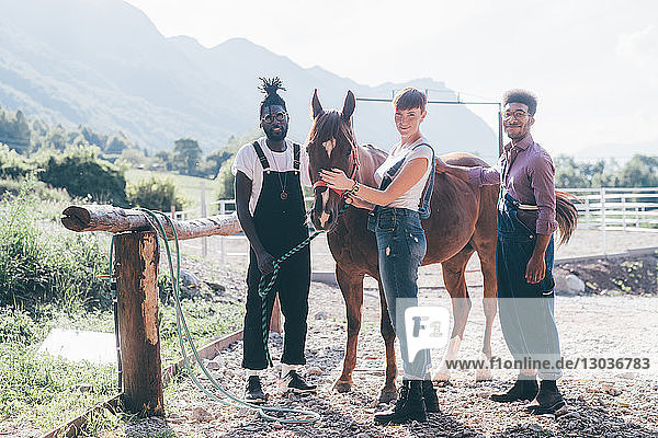 Junge Frauen und Männer  die sich auf dem ländlichen Reitplatz mit dem Pferd verbinden  Primaluna  Trentino-Südtirol  Italien