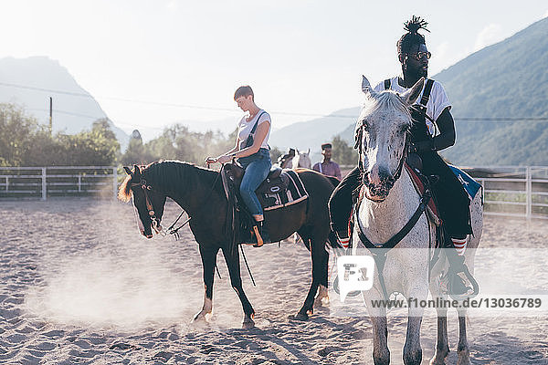 Junger Hipster-Mann und Frau reiten auf Pferden in ländlicher Reitarena  Primaluna  Trentino-Südtirol  Italien