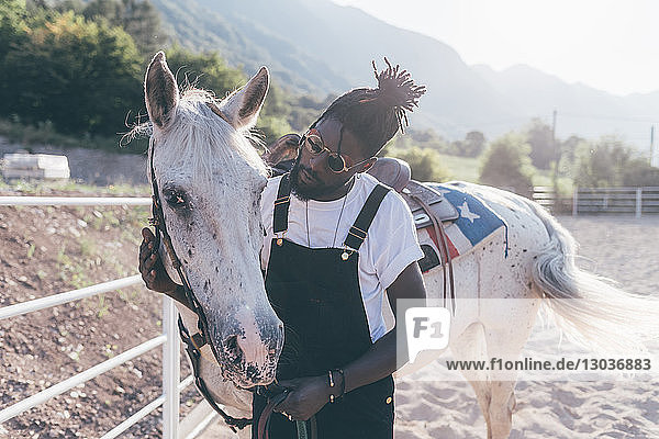 Kühler junger Mann verbindet sich mit Pferd in ländlicher Reitarena