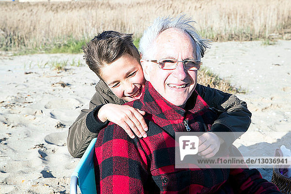 Älterer erwachsener Mann mit Enkel am Strand
