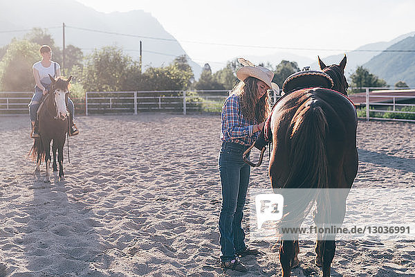 Cowgirl sattelt Pferd in ländlicher Reitarena  Primaluna  Trentino-Südtirol  Italien