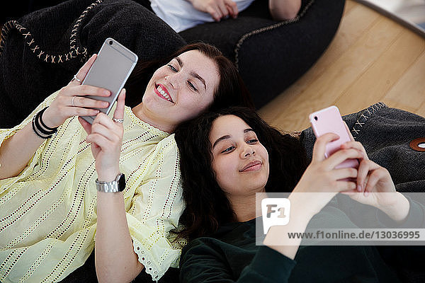 Schulfreunde liegen auf Sitzsäcken und schreiben in der Schule SMS