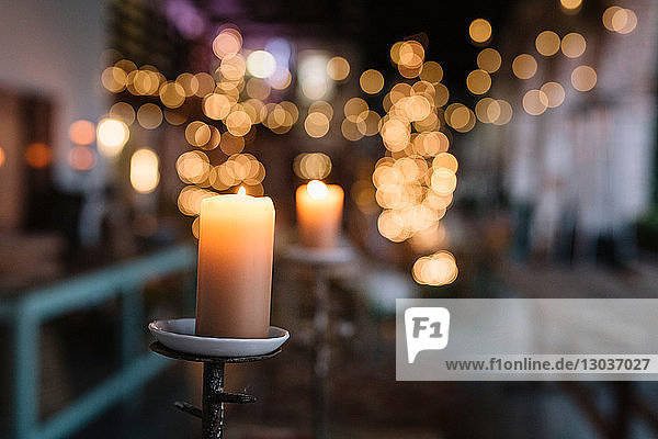 Close up of lit candle in cafe with decorative lights