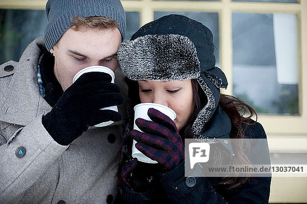 Junges Paar mit Winterhüten trinkt Kaffee zum Mitnehmen