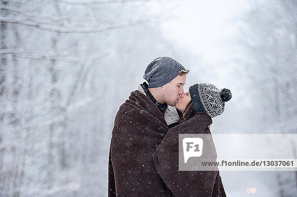 Romantisches junges Paar küsst sich im verschneiten Wald  Ontario  Kanada