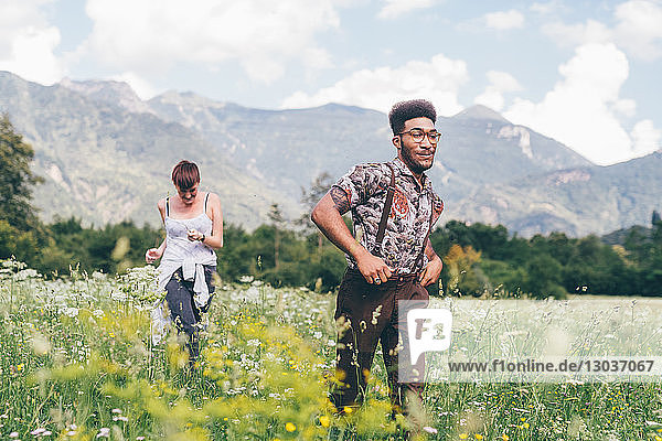 Junger Mann und Frau rasen durch eine Wildblumenwiese  Primaluna  Trentino-Südtirol  Italien