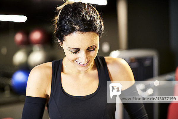 Kopf- und Schulteraufnahme einer lächelnden Sportlerin im Fitnessstudio