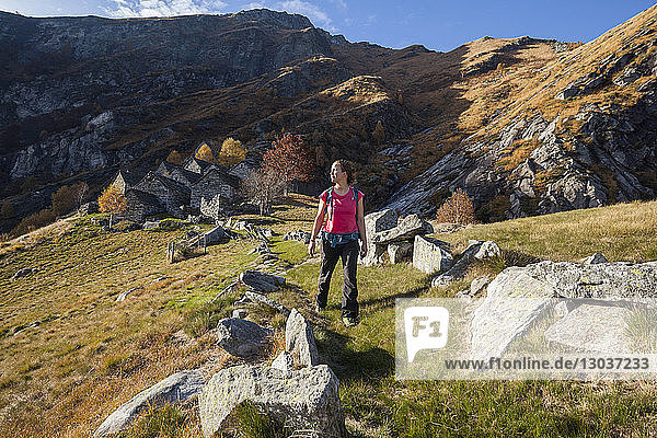 Totale Aufnahme einer einzelnen Wanderin  die einen Pfad vom Monte del Corgel oberhalb von Corippo  Kanton Tessin  Schweiz  hinunterwandert