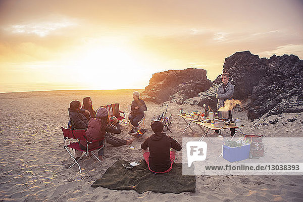 Freunde zelten bei Sonnenuntergang am Strand