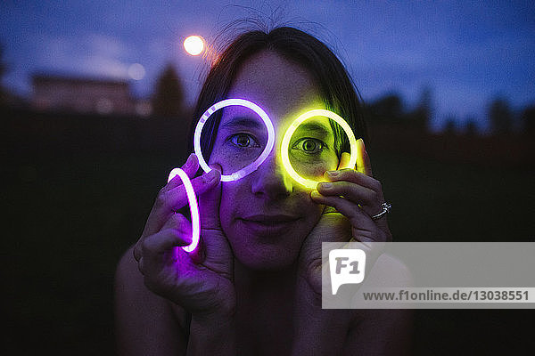 Portrait of woman holding neon bands around her eyes