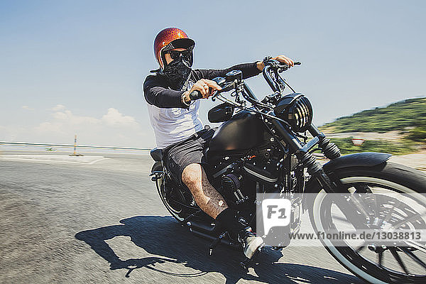 Mann fährt Cruiser-Motorrad auf Straße gegen Himmel