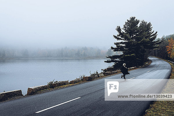 Rear view of woman running on road during foggy weather