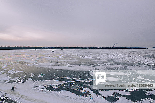 Szenische Ansicht eines zugefrorenen Flusses vor bewölktem Himmel