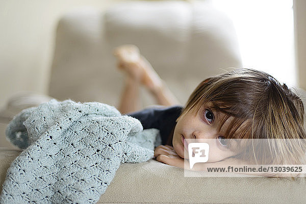 Portrait of girl lying on sofa at home