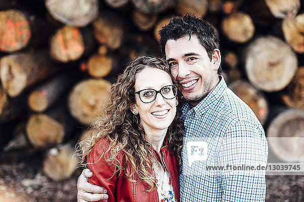 Porträt eines glücklichen Paares an Holzscheiten stehend