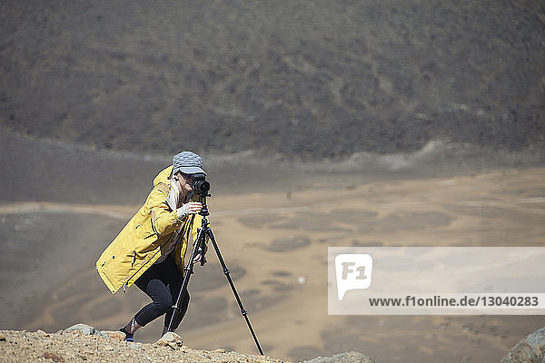 Frau fotografiert mit Kamera auf Stativ in der Wüste