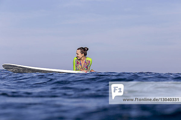 Frau mit Surfbrett auf dem Meer gegen den Himmel